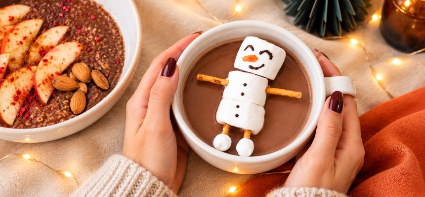 Ženské ruky držia hrnček kakaa so snehuliakom z marshmallow